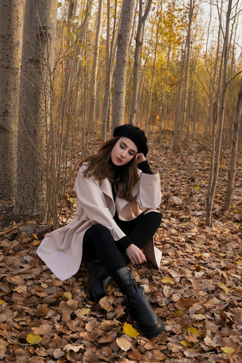 a woman sitting on leaves in a forest