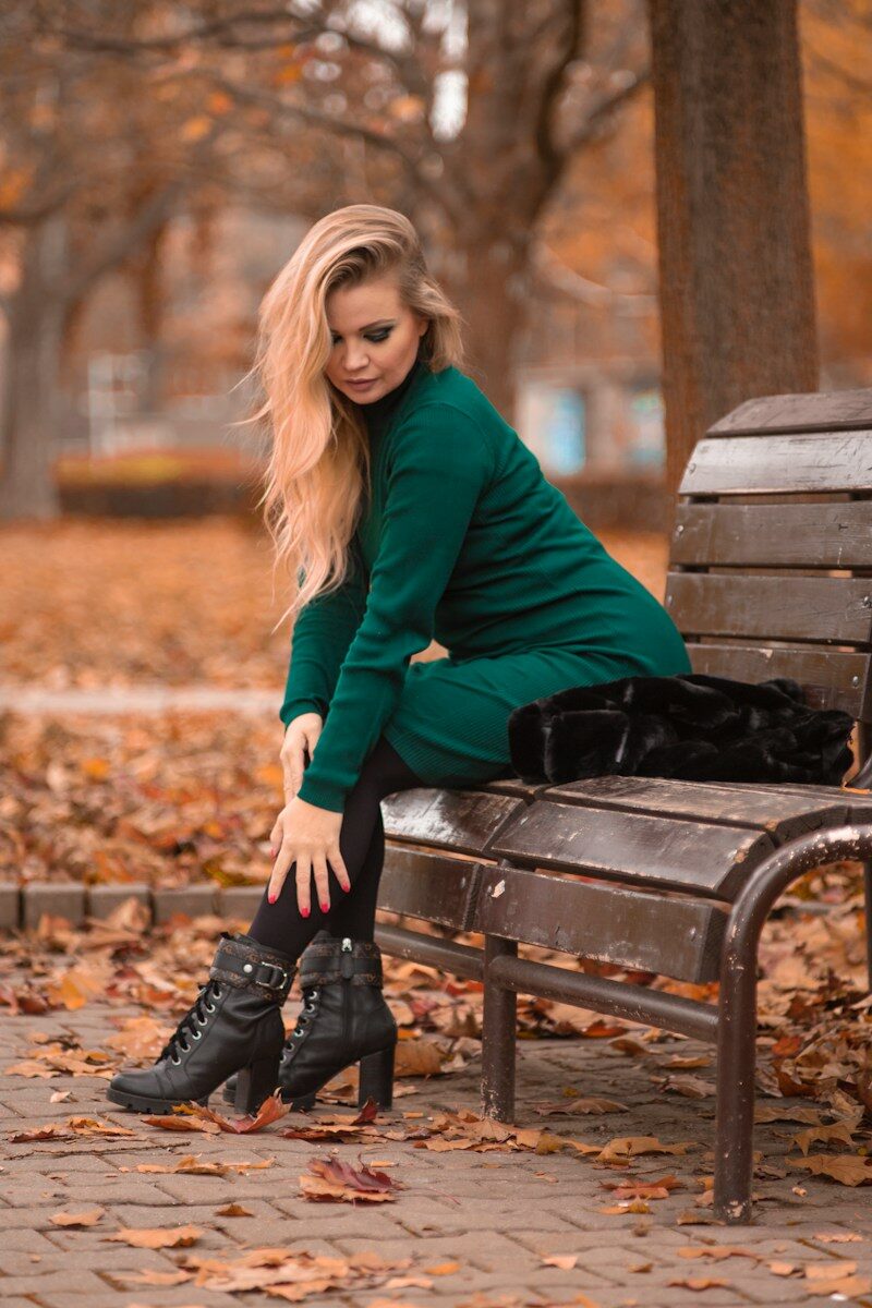 woman in blue long sleeve shirt sitting on brown wooden bench
