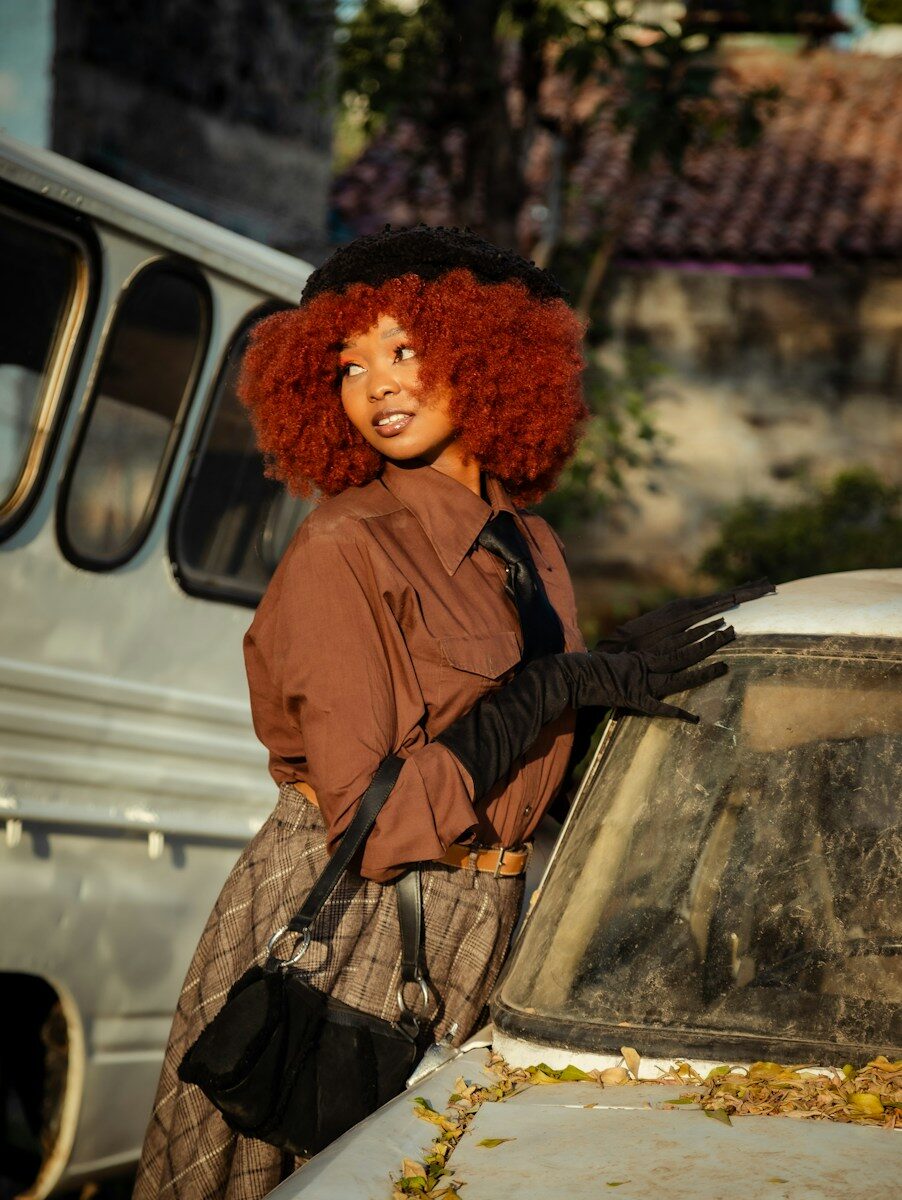 A woman with red hair standing next to a car